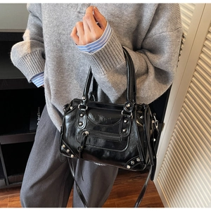 Detail of black glossy Boston bag with silver studs and industrial straps on a shoulder