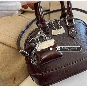 Détail du sac à main bordeaux brillant avec sa mini pochette suspendue et sa texture