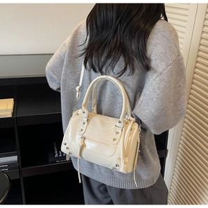 Detail of cream white studded motorcycle bag with leather tassels and metallic rivets