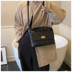 Bolso bandolera acolchado negro con cierre giratorio dorado y asa en una modelo