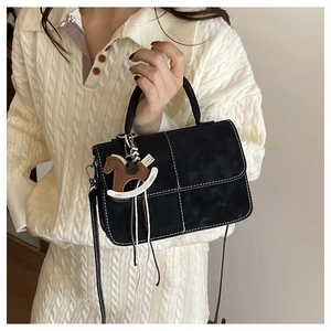 Close-up of black crossbody bag with white contrast stitching and horse charm