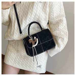 Close-up of black matte tote bag with contrast white stitching and leather horse charm