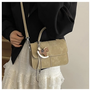 Detail of khaki crossbody bag with matte texture, flap design, and horse charm ornament