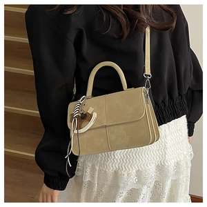 Detail of khaki crossbody bag with textured stitching and decorative horse charm accessory