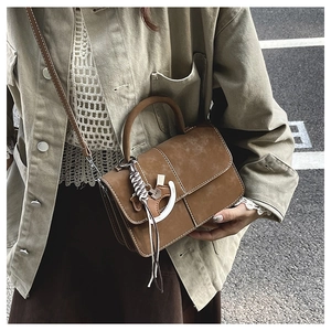 Detail of vintage brown suede crossbody bag with decorative horse charm and shoulder strap