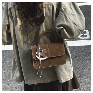 Rear view of woman wearing a brown suede crossbody bag with a cute horse charm