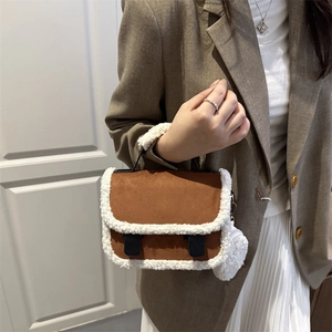 Brown suede and faux shearling saddle bag with a small plush charm and crossbody strap