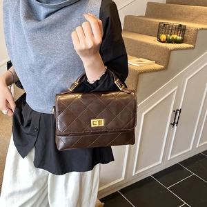 Bolso acolchado marrón oscuro con cierre dorado y asa superior en una modelo