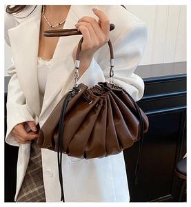 Detail of dark brown leather bucket bag showing pleated cloud design and round handle