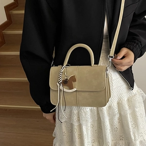 Chic beige crossbody square bag with horse charm and woven rope on wooden stairs