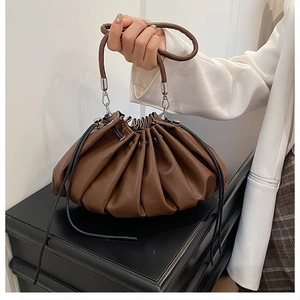 Detail of dark brown ruched bucket bag with drawstring closure and ring handle