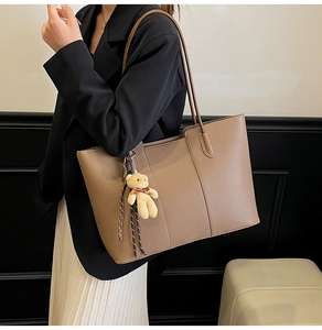 Brown lychee grain leather tote bag with cute plush bear charm on model's shoulder