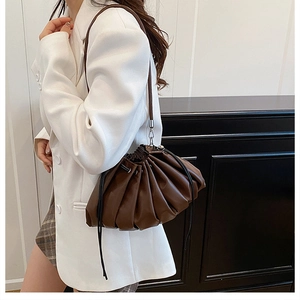Detail view of dark brown pleated cloud bag with black drawstring and metal hooks