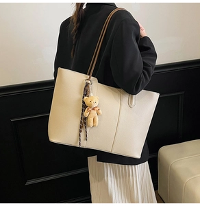 Off-white tote bag with lychee texture and brown strap shown on a model's shoulder