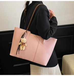 Detail of pink faux leather tote bag with vertical stitching and plush bear charm