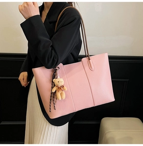 Pink leather tote bag with litchi texture detail featuring a plush bear and ribbon