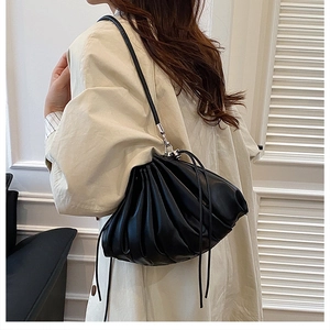 Detailed view of black pleated shoulder bag with soft leather texture and drawstring design