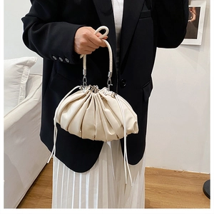 Detail of a creamy white pleated bucket bag with a stylish drawstring closure and leather texture