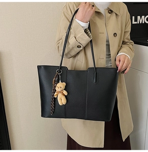 Detail of black pebbled leather tote bag with teddy bear charm and plaid silk scarf