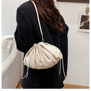 Detail of cream pleated bucket bag showing soft PU leather texture and silver hardware