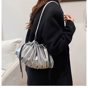 Macro shot of silver pleated metallic cloud bag showing textured fabric and drawstring