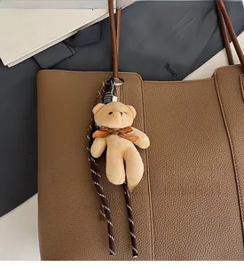 Detail of brown litchi grain leather tote bag with a cute plush bear charm accessory