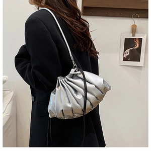 Close-up of metallic silver pleated cloud bag with black drawstring straps on model