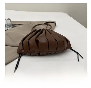 Detail view of the pleated dark brown leather handbag with a drawstring base design