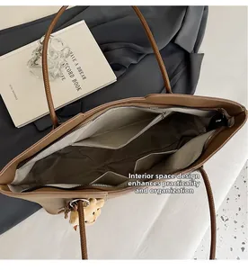 Detail view of large brown tote bag interior with zipper pockets and plush bear charm