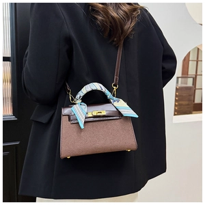 Detail of cross-body handbag with matte texture and silk scarf wrapped on handle