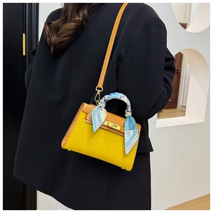 Detail of yellow and brown crossbody bag featuring a striped silk scarf and gold metal clasp