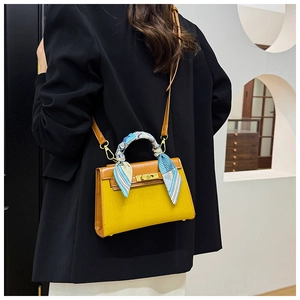 Yellow leather Kelly bag with blue silk scarf handle shown on a black blazer