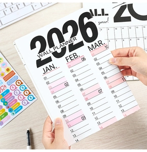 Detailed 2026 vertical wall planner with color-coded stickers on a modern office desk