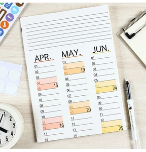 Detailed flat lay of 2026 monthly planner pages with color-coded dates on wood background