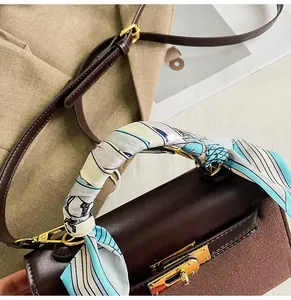 Close-up of brown leather bag with golden twist-lock and silk scarf wrapped handle