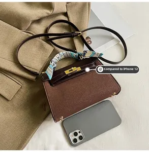 Mini suede handbag size comparison with iPhone 12 featuring contrast stitching and gold lock