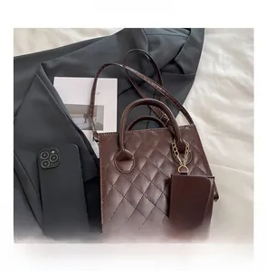 Dettaglio borsa trapuntata marrone con mini pochette coordinata e finiture dorate