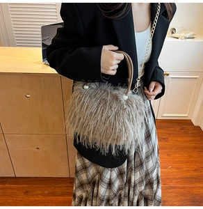 Detail einer hellbraunen Kunstpelz-Handtasche mit Perlengriff und Goldkette am Model