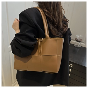 Gros plan du sac seau tressé en caramel montrant le motif de tissage à carreaux