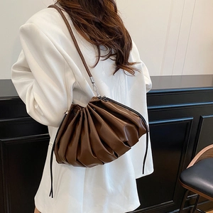 Chic brown ruched bucket bag with drawstring closure on model in white blazer