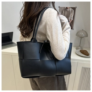 Détail d'un sac seau tressé noir montrant sa grande capacité et ses anses en cuir