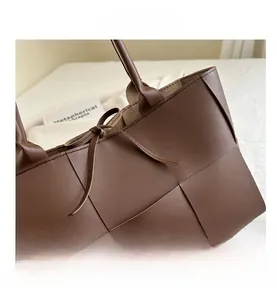 Détail d'un sac seau tressé marron avec fermeture par cordon en cuir et coutures précises