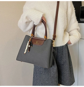 Detail der grauen Webstruktur und des braunen Lederbesatzes an der Retro-Tasche