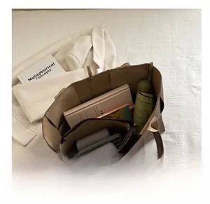 Vue macro de l'intérieur d'un grand sac seau marron avec pochette amovible et articles