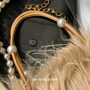 Detailansicht der Kunstpelz-Handtasche mit eleganten weißen Perlen und Metallkettenriemen
