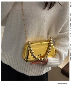 Gros plan sur la pochette dorée avec poignée en perles et surface effet miroir