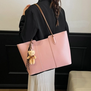 Pink lychee texture tote bag with brown straps and cute bear pendant shown on model