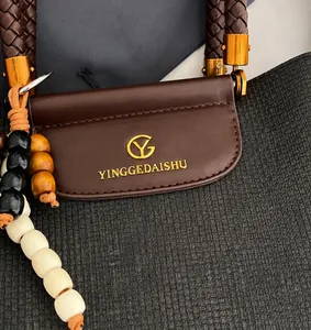 Detail der Kaffeebraunen Ledertasche mit geflochtenem Griff und Holzperlen-Quaste
