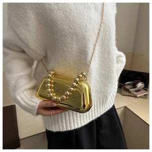Détail du sac boîte miroir doré avec poignée perlée et fine bandoulière chaîne