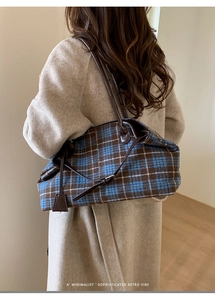 Detail of wool plaid tote bag featuring blue and brown check pattern and leather straps